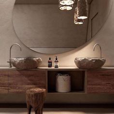 a bathroom with two sinks and a large round mirror above the sink is illuminated by three lights