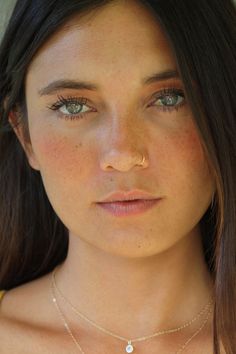 a close up of a woman wearing a necklace with a small diamond on it's neck