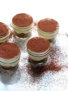 four small jars filled with brown powder on top of a table