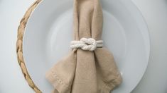 a white plate topped with a napkin tied to it's side next to a rope