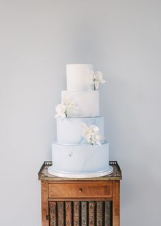 4 tier dusty blue marble ombre wedding cake with clusters of sugar orchids and silver leaf trailing upwards Dusky Blue Wedding Cake, Dusty Blue Wedding Cake Ideas, Blue Marble Wedding Cake, Baby Blue Wedding Cake, Blue Ombre Wedding Cake, Wedding Cake Designs Blue, Dusty Blue Wedding Cake, Wedding Cake 4 Tier, Blue Ombre Wedding