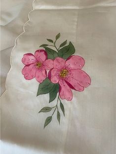 two pink flowers on white linen with green leaves and stems painted on the side of it