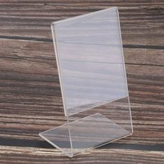 a clear acrylic sign stands on a wooden surface with wood planks in the background