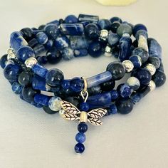 This unique jewelry piece is made with a variety of sodalite beads accented with silver tone beads and a silver tone dragonfly charm. It's made on durable stretch cord that measures approx. 36" at the longest so it can be worn as a wrap bracelet or a necklace! Blue Sodalite Hand-strung Beaded Bracelets, Blue Sodalite Gemstone Beaded Bracelets, Silver Lapis Lazuli Beaded Bracelets For Healing, Spiritual Sodalite Gemstone Beaded Bracelets, Adjustable Sodalite Gemstone Beaded Bracelets, Silver Lapis Lazuli Hand-strung Beaded Bracelets, Adjustable Sodalite Beaded Bracelets, Messy Bracelet, Handmade Bracelets Tutorial