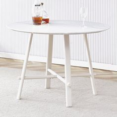 a white table with a bottle and glass on it