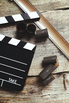 a movie clapper next to two rolls of tape on top of a wooden table