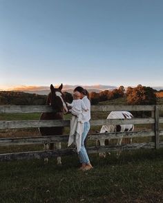 a woman standing next to a horse on top of a lush green field