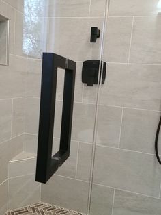 a bathroom with a glass shower door next to a toilet paper dispenser