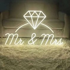 a neon sign that says mr and mrs on it in front of a couch with fur