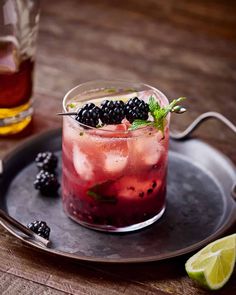 a drink with blackberry and lime on a tray