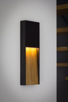 a wall mounted light with a wooden frame on it's side and a yellow light in the middle