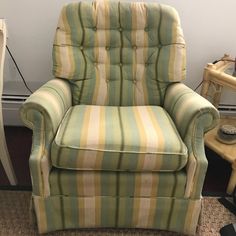 a green and yellow striped chair next to a small table with a lamp on it