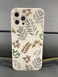 an iphone case with flowers and butterflies on it, sitting on a car seat in the passenger