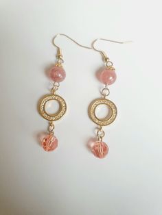 Soft pink vibes are calming and nurturing. Strawberry quartz produces exactly that. This stunning handmade pair you're looking at comprises one 8 mm strawberry quartz and one pink Swarovski crystal on each piece, decorated with a gold Swarovski -studded disk and floral gold bead caps. The result is a pair of stylish ear rings that accentuates your matching attire.  This beauty is 5 cm long from the base of the gold ear wires.  Healing properties: Strawberry Quartz helps to attract true love or soul mate. It also helps to balance the body, soul, and mind. Thank you for looking at this listing at Crystal Bijoux by Emmie. You can explore all our handmade, one-of-a-kind, crystal jewelry collection here:  https://www.etsy.com/shop/crystalbijouxbyemmie We also custom make crystal jewelry based o Hypoallergenic Pink 14k Gold Filled Jewelry, Pink 14k Gold Filled Dangle Jewelry, Pink Crystal Dangle Earrings With Ear Wire, Pink Dangle Crystal Earrings For Gift, Pink Wire Wrapped Beaded Earrings With Round Beads, Pink Wire Wrapped Beaded Earrings, Handmade Pink Crystal Drop Earrings, Pink Crystal Round Earrings For Gift, Pink Wire Wrapped 14k Gold-filled Jewelry