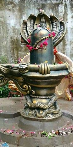 an ornate fountain in the middle of a garden with pink flowers on it's head