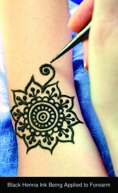 a henna tattoo being applied to a woman's arm with a pen on it