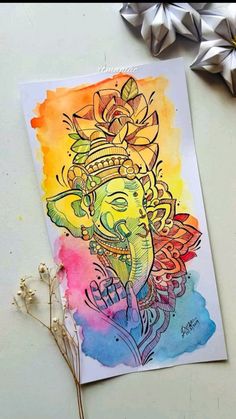 an art work with watercolors on paper and some dried flowers next to it