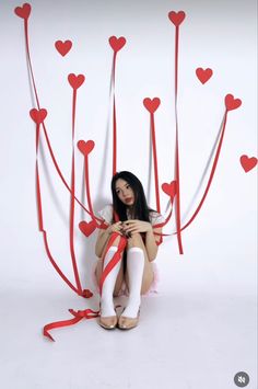 a woman sitting on the ground with red hearts attached to her legs and holding a cell phone