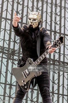 a man wearing a mask and holding a guitar