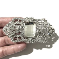 "A 1920s vintage style Gatsby wedding Art Deco bridal brooch sash pin featuring ornate geometric details made of clear swarovski crystals in silver rhodium or gold plated finish. This bridal brooch can be as a dress jewelry or on bridal bouquet. Brooch measures about 1 1/2\"(3.8cm) x 3\"(7.6cm) at its widest. View matching pieces or similar designs at https://etsy.me/2Mu6wjC and https://etsy.me/2tvK27M View all brooch pins at https://etsy.me/1eEBStU" Silver Art Deco Brooches For Wedding, Silver Art Deco Wedding Brooch, Silver Art Deco Wedding Brooches, Swarovski Crystal Dress, Deco Wedding Dress, Art Deco Wedding Dress, Wedding Art Deco, Bridal Brooch, Wedding Dress Jewelry