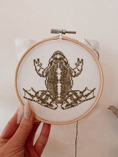 someone is holding up a cross stitch project