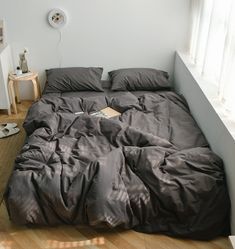 an unmade bed sitting on top of a hard wood floor next to a window