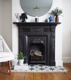 a fireplace in a living room with a mirror on the wall above it and a potted plant next to it