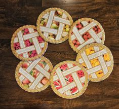 four pies with different designs on them sitting on top of a wooden table next to each other