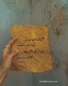 a person holding up a piece of paper with writing on it in arabic and english