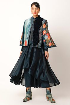 Midnight blue jacket with cape sleeves, abstract pattern patch work panels, multi color floral thread, applique and zari embroidery. Paired with flared anarkali with high-low hem and straight pant.
Components: 3
Pattern: Embroidered and Printed
Type Of Work: Applique, Thread and Zari Work
Neckline: Jacket: Band Collar
Sleeve Type: Jacket: Cape Sleeves
Fabric: Chanderi, Velvet, Cotton Slub
Color: Blue
Other Details: 
Panelled jacket
Length:
Cape: 23.5 inches
Anarkali Front: 38 inches
Anarkali Bac Silk Anarkali Set With Long Sleeves For Transitional Seasons, Anarkali Kurta With Cape Sleeves And Dupatta, Traditional Cape-shaped Dupatta For Designer Wear, Silk Outerwear With Resham Embroidery For Designer Wear, Spring Long Sleeve Cutdana Anarkali Set, Silk Outerwear With Zari Work And Long Sleeves, Festive Long Sleeve Outerwear With Cutdana, Designer Chanderi Outerwear With Resham Embroidery, Festive Silk Outerwear With Traditional Drape