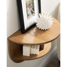 a wooden shelf with two white flowers and a framed photo on it's side