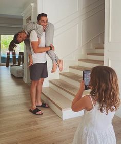 a man holding a woman on his shoulders while she takes a photo with her phone