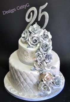 a white wedding cake with roses and the number twenty five on it's side