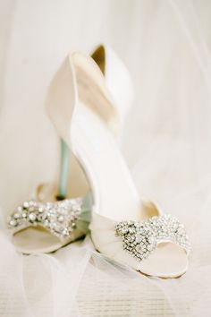 a pair of wedding shoes with bows and pearls on the heels are sitting next to each other