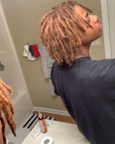 a man with dreadlocks standing in front of a bathroom mirror