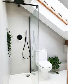 a white toilet sitting next to a shower in a bathroom under a slanted roof