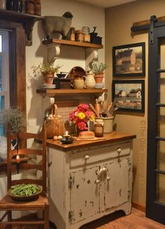 a kitchen with an old fashioned cabinet and wooden chairs in front of the window is filled with pots, pans, and other items