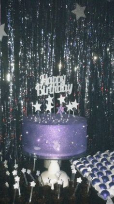 a purple birthday cake sitting on top of a table