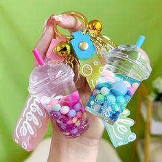 a person holding two small plastic cups with candy in them and a keychain