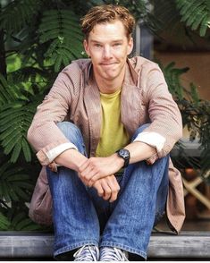 a man sitting on top of a window sill with his hands folded in front of him