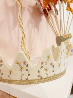 a white crown with flowers on it sitting on a table next to other items and decorations