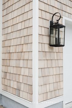 a light on the side of a building next to a white door and brick wall