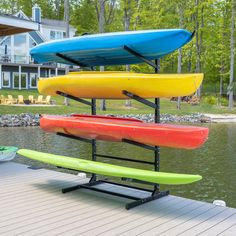 three surfboards are stacked on top of each other in front of a lake house