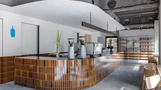 the interior of a modern restaurant with wood accents and stainless steel counter tops, along with wooden chairs