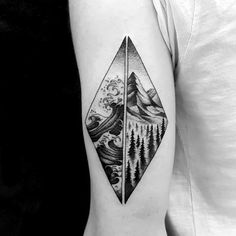 a man's arm with a mountain and forest tattoo on it, which has an arrow