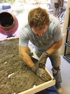 a man is working in the dirt with gloves on and his hands resting on a piece of wood