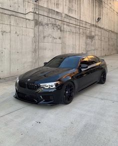 a black car parked in front of a building with concrete walls and cement flooring