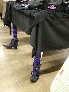 a table topped with lots of black clothing and purple socks on it's legs