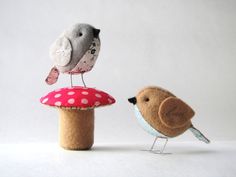 two small birds sitting on top of a mushroom