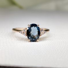 an oval blue sapphire and diamond ring on a white surface